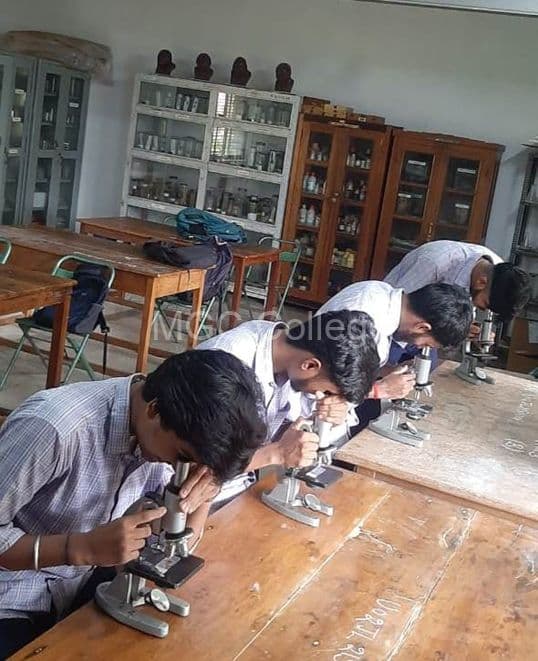 Students observing slides under compound microscopes
