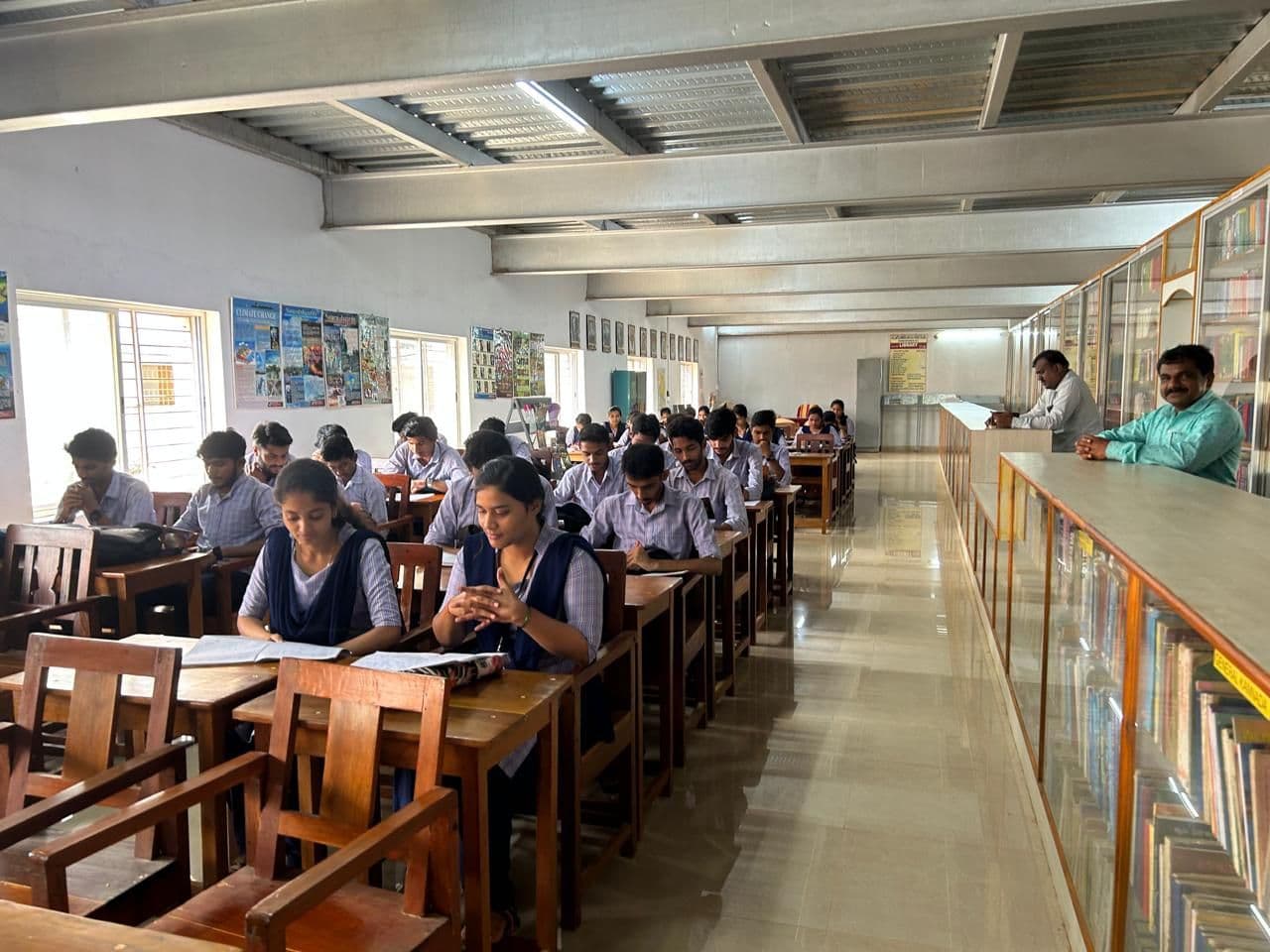 Students reading at tables beside the bookshelves